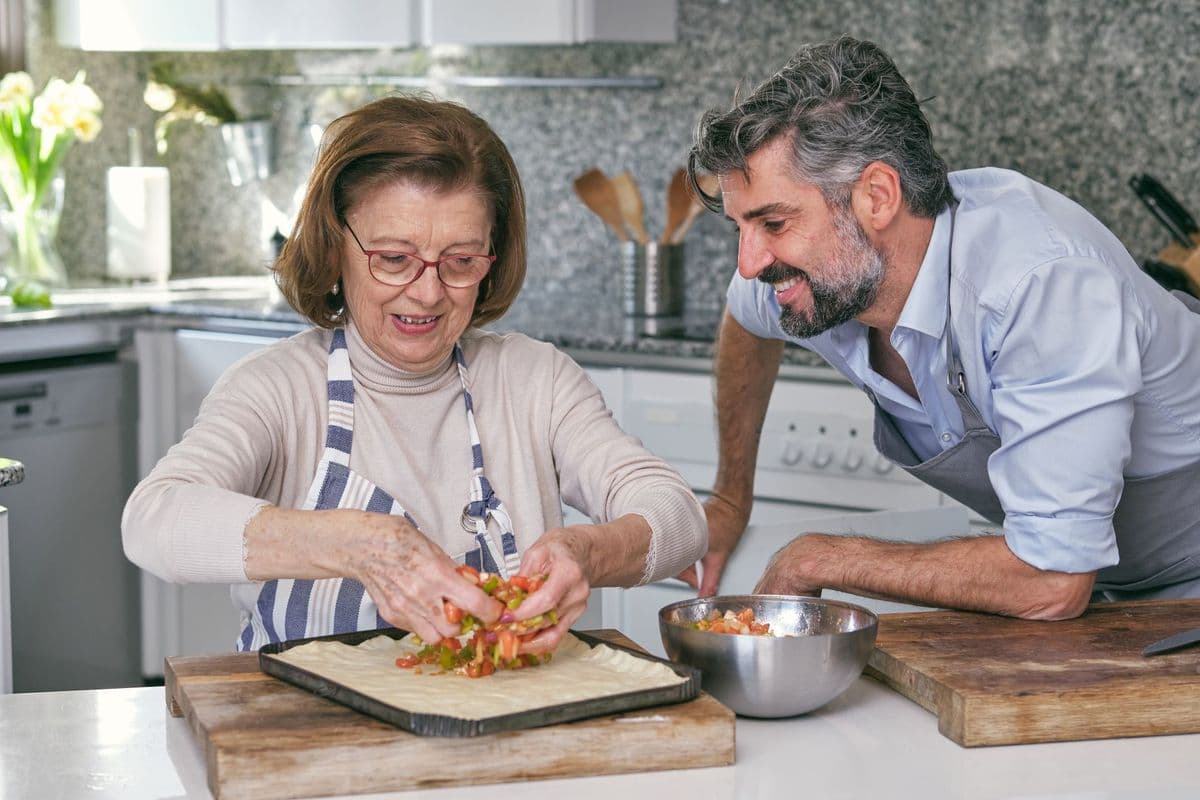 An older woman and young man cook together.