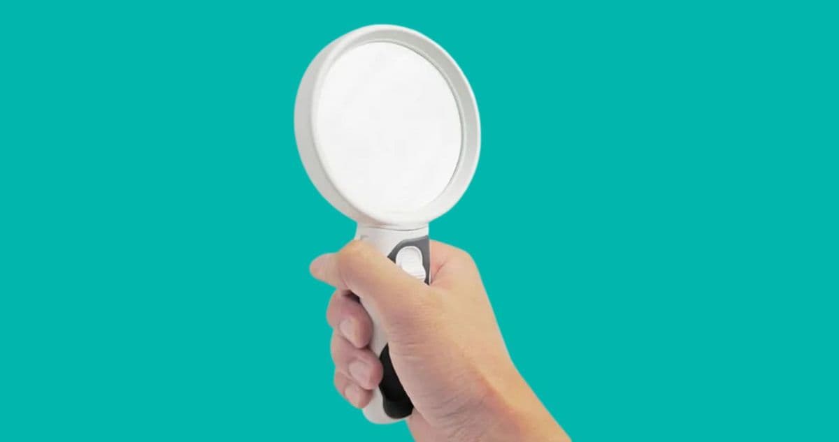 A white magnifying glass being held by a hand