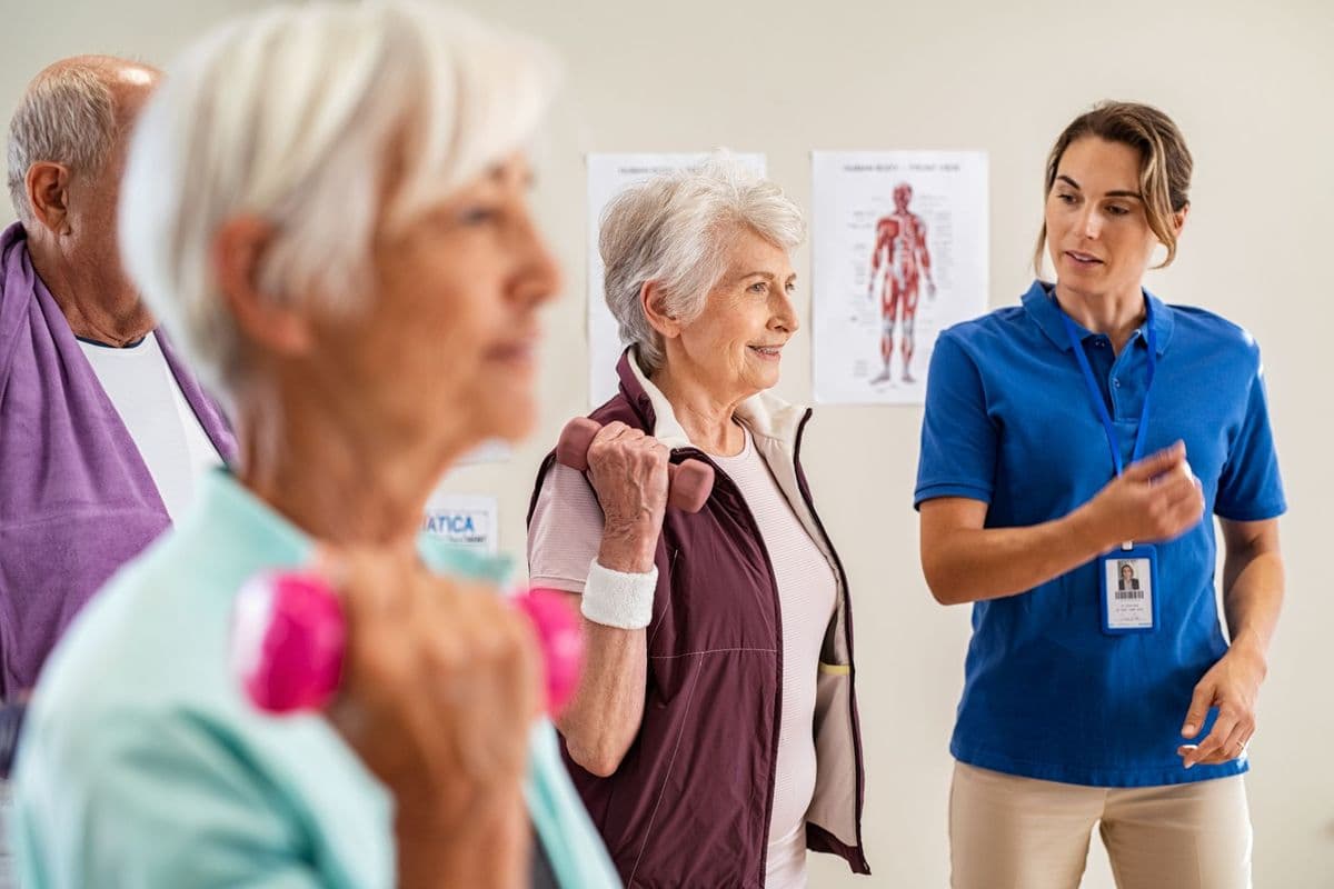 A health professional giving instructions to older women doing exercises with dumbbells.