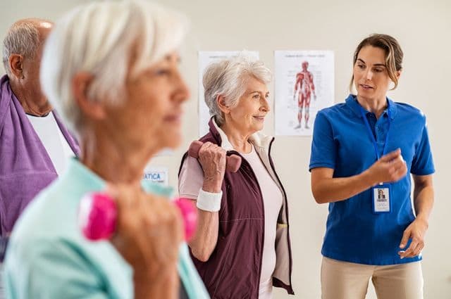 A health professional giving instructions to older women doing exercises with dumbbells.