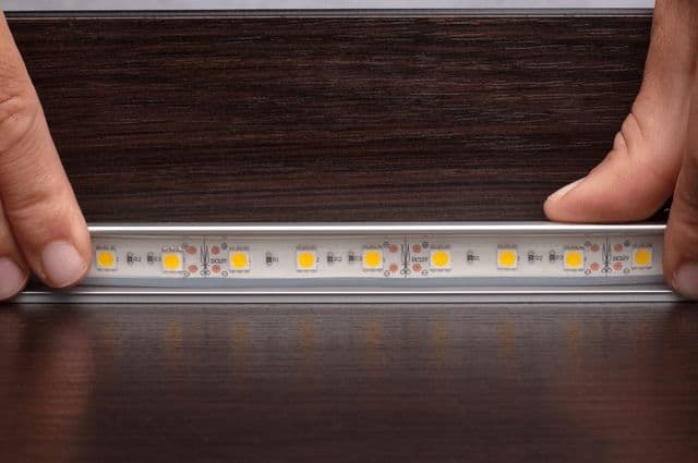 A person installing a strip of LED lighting