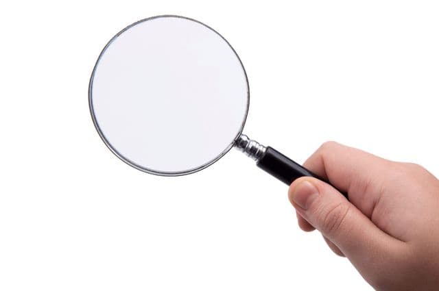 A hand holding a magnifying glass