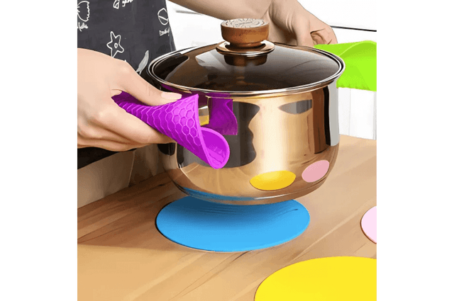 A saucepan being carried with and placed on colourful silicone mats