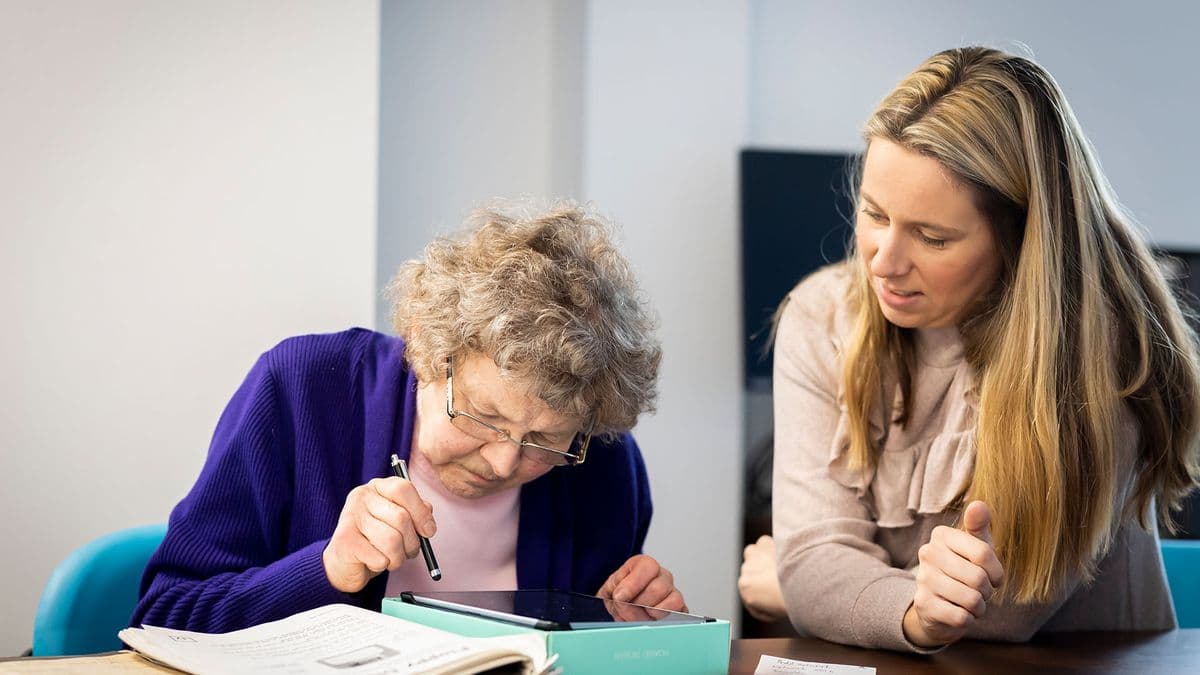 Older woman using a touchpad while seated next to a younger woman