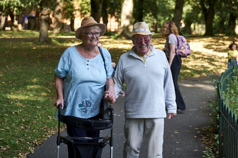 Older couple smiling and walking through the park together