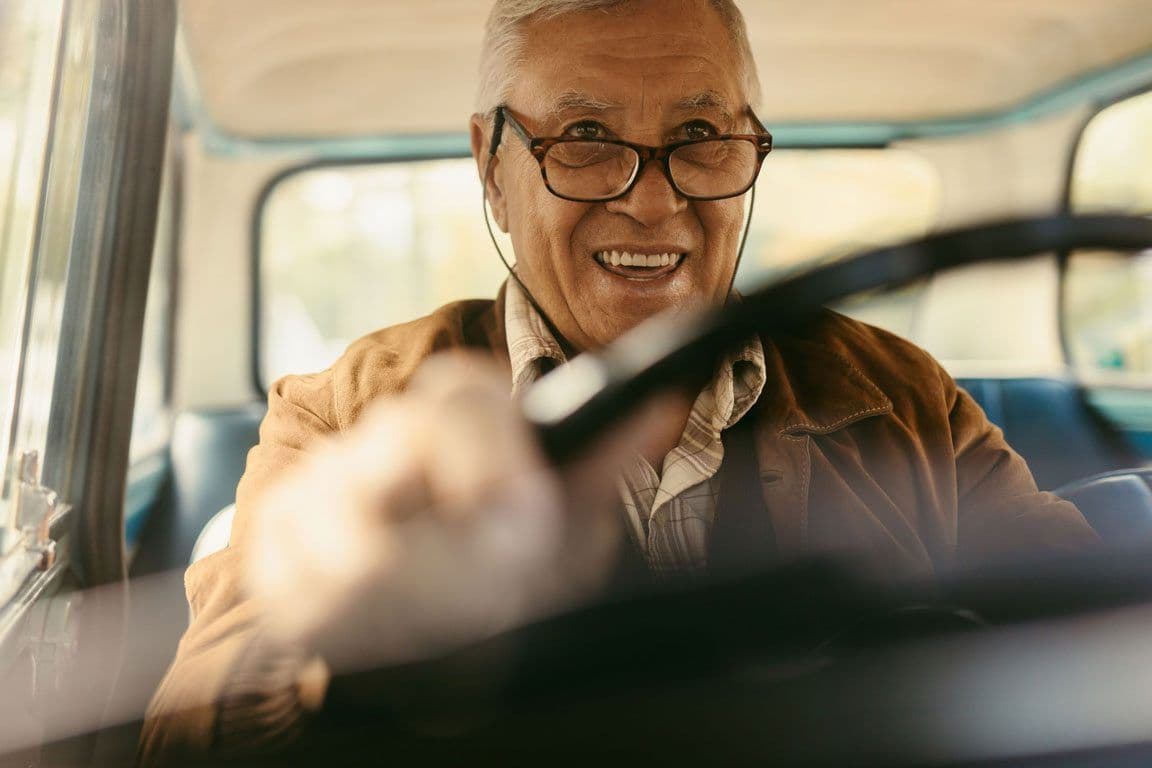 An older man happily driving his car