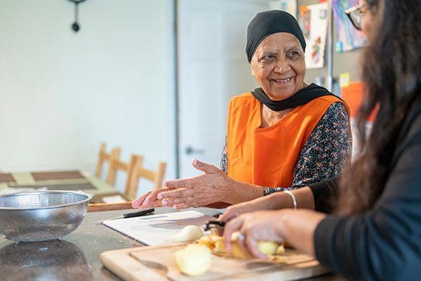 An older woman and a younger woman preparing food in the kitchen together