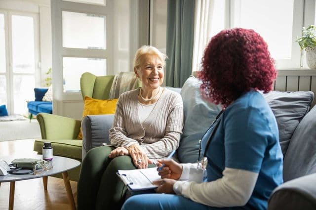 An older woman and adult woman in nursing scrubs happily completing a checklist together