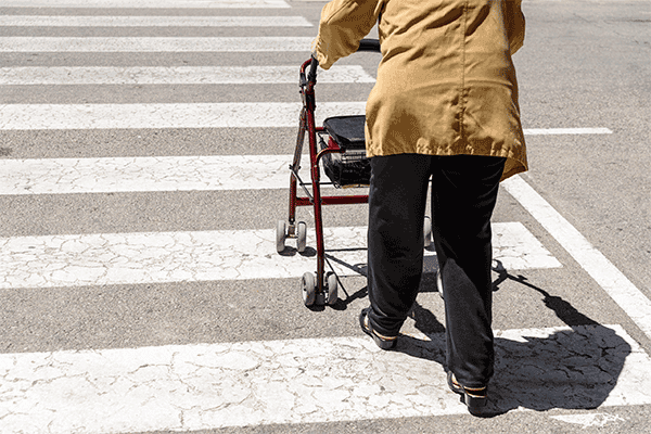 Older woman using a walker to cross the road