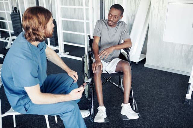 A health professional talking to a man in a wheelchair.