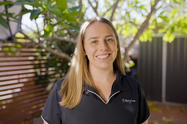 Physiotherapist Gina smiling in her client's backyard. 