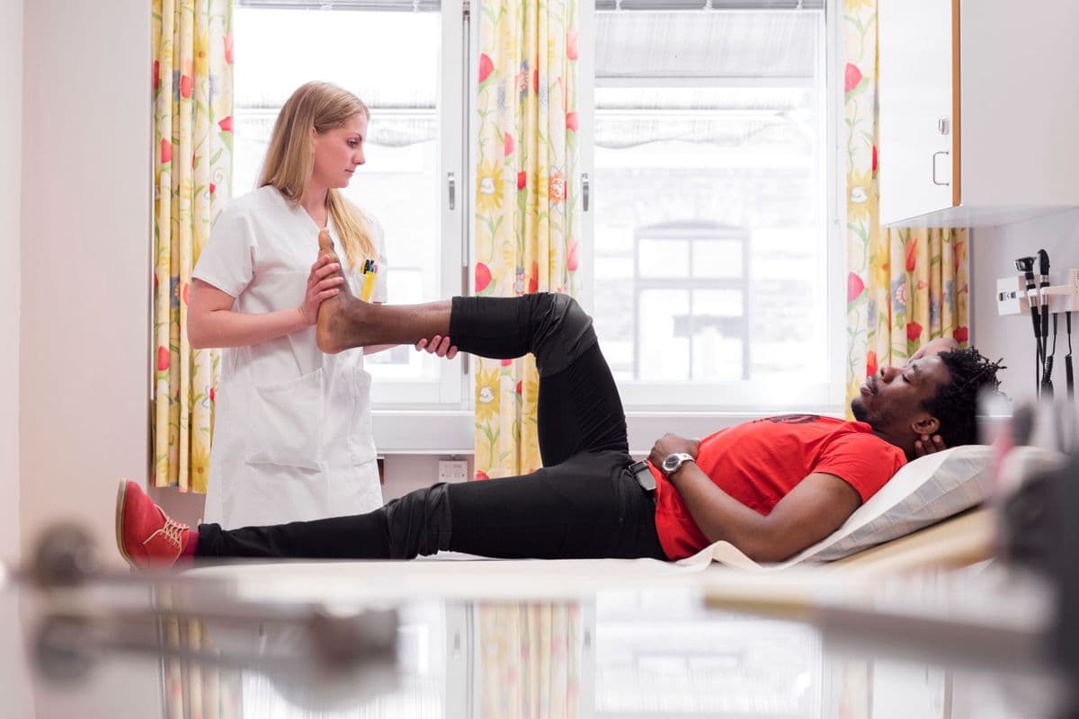 A physiotherapist lifting a patient's leg while doing manual therapy.