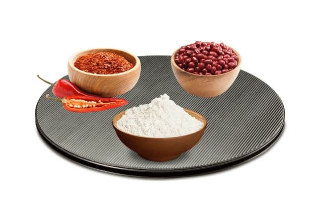 Three bowls of cooking ingredients on a black rotating server