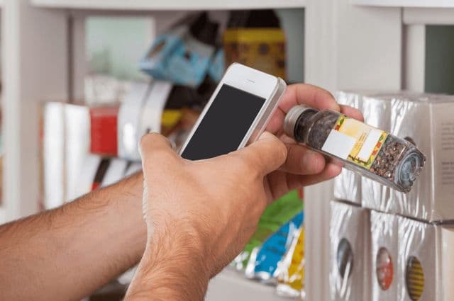 A person using a smart phone to scan a supermarket product