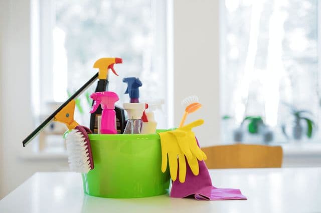 A small green bucket holding cleaning products