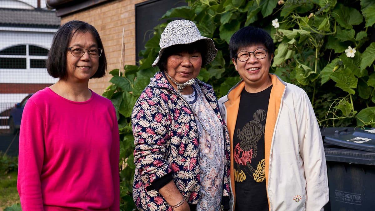 Three older women standing together in a garden