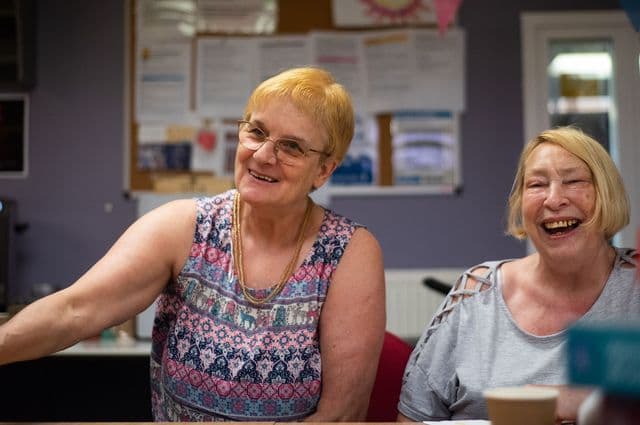 Two older women laughing at a table together