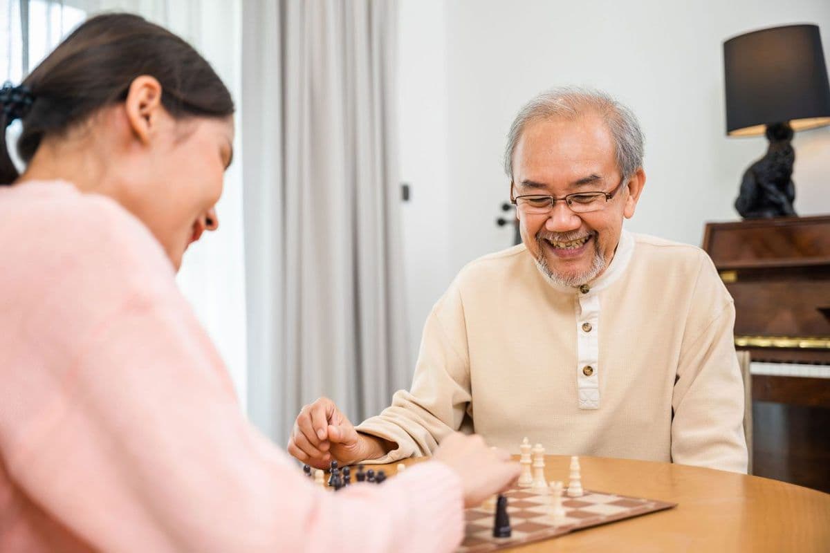 An adult woman and an older man playing chess together