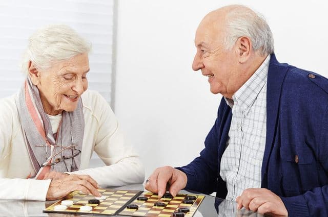 elderly couple playing checkers