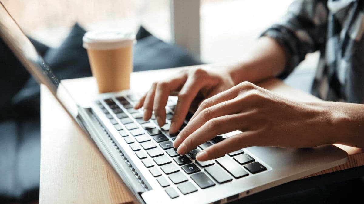 Sending thank you feedback on a laptop with coffee