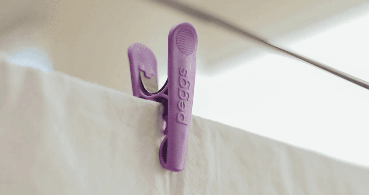 A purple clothes peg holding a white sheet in place