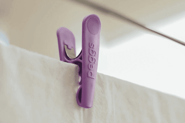 A purple clothes peg holding a white sheet in place