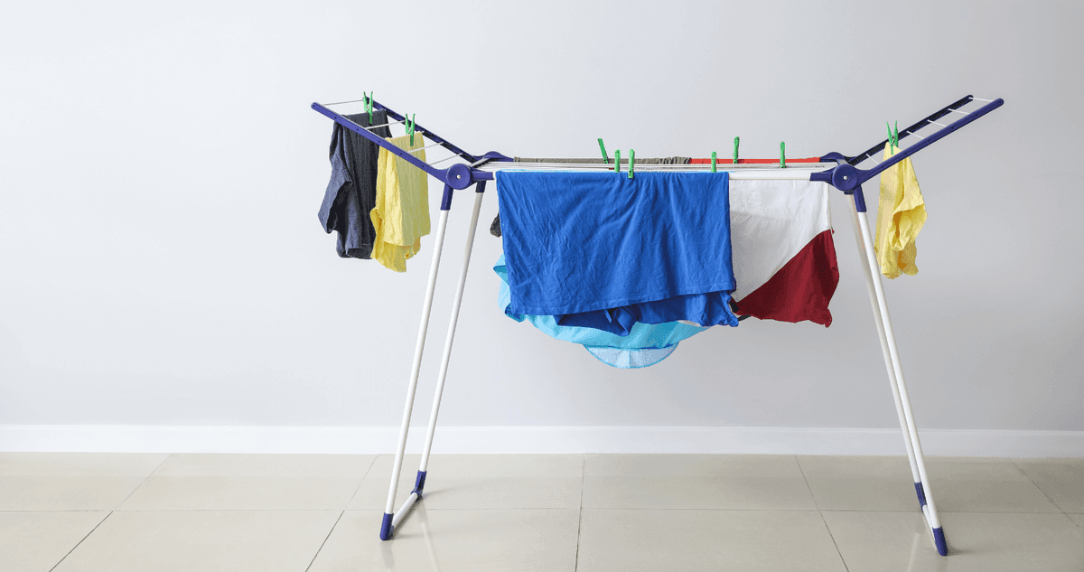 A freestanding drying rack with clothes on it
