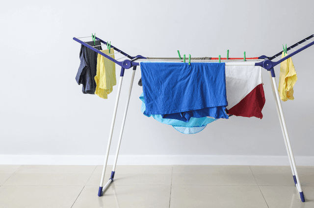 A freestanding drying rack with clothes on it