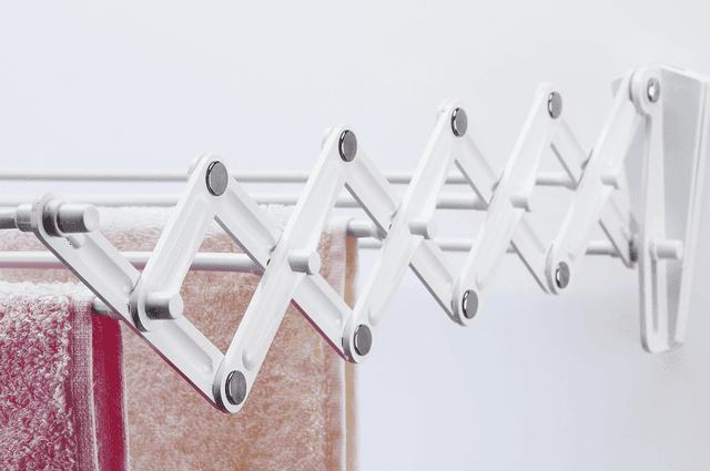 A wall mounted drying rack holding some towels
