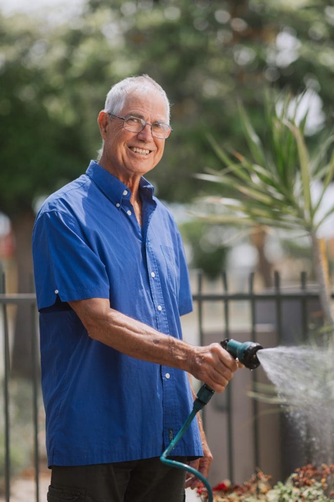 Elderly man watering garden