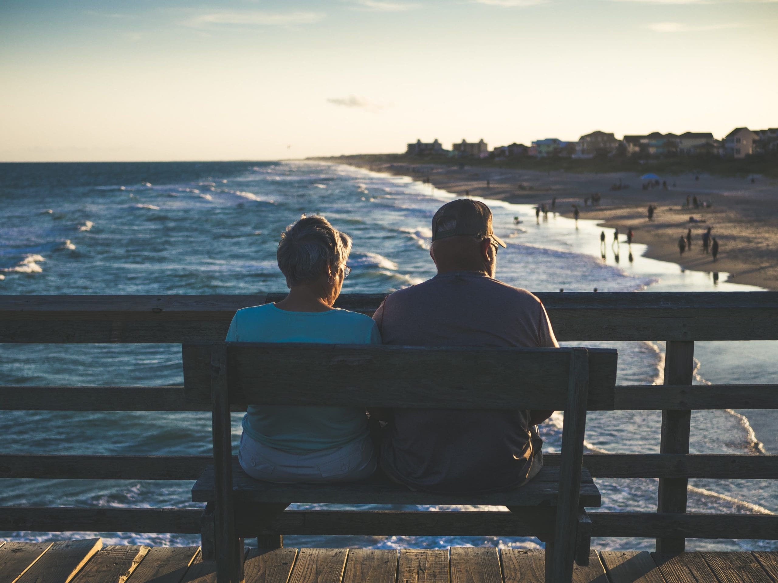 Older couple sitting on a bench looking at the beach