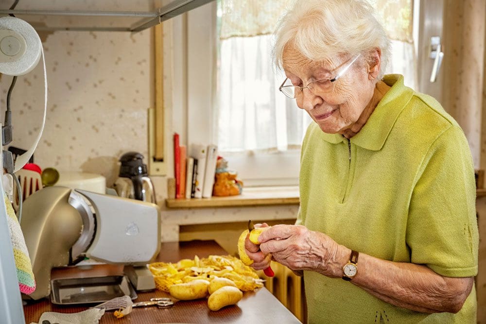Elderly lady preparing potatoes
