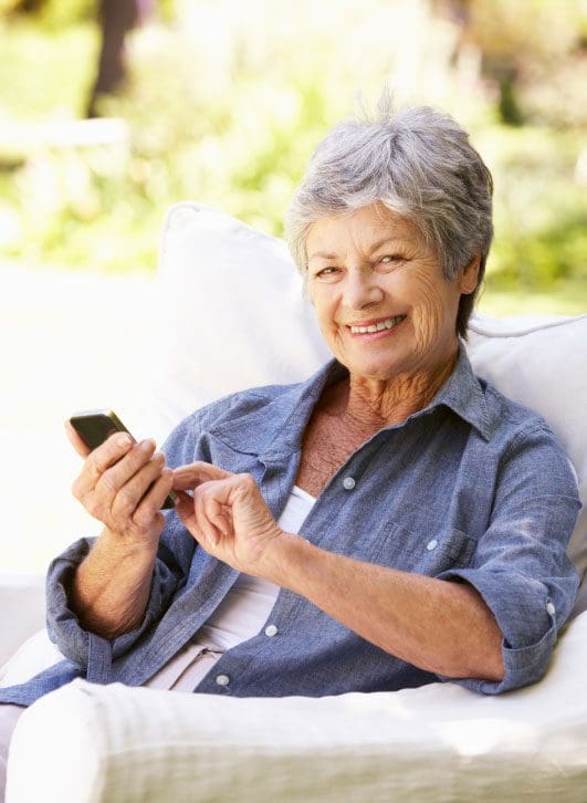 Elderly lady sitting in an armchair with mobile phone