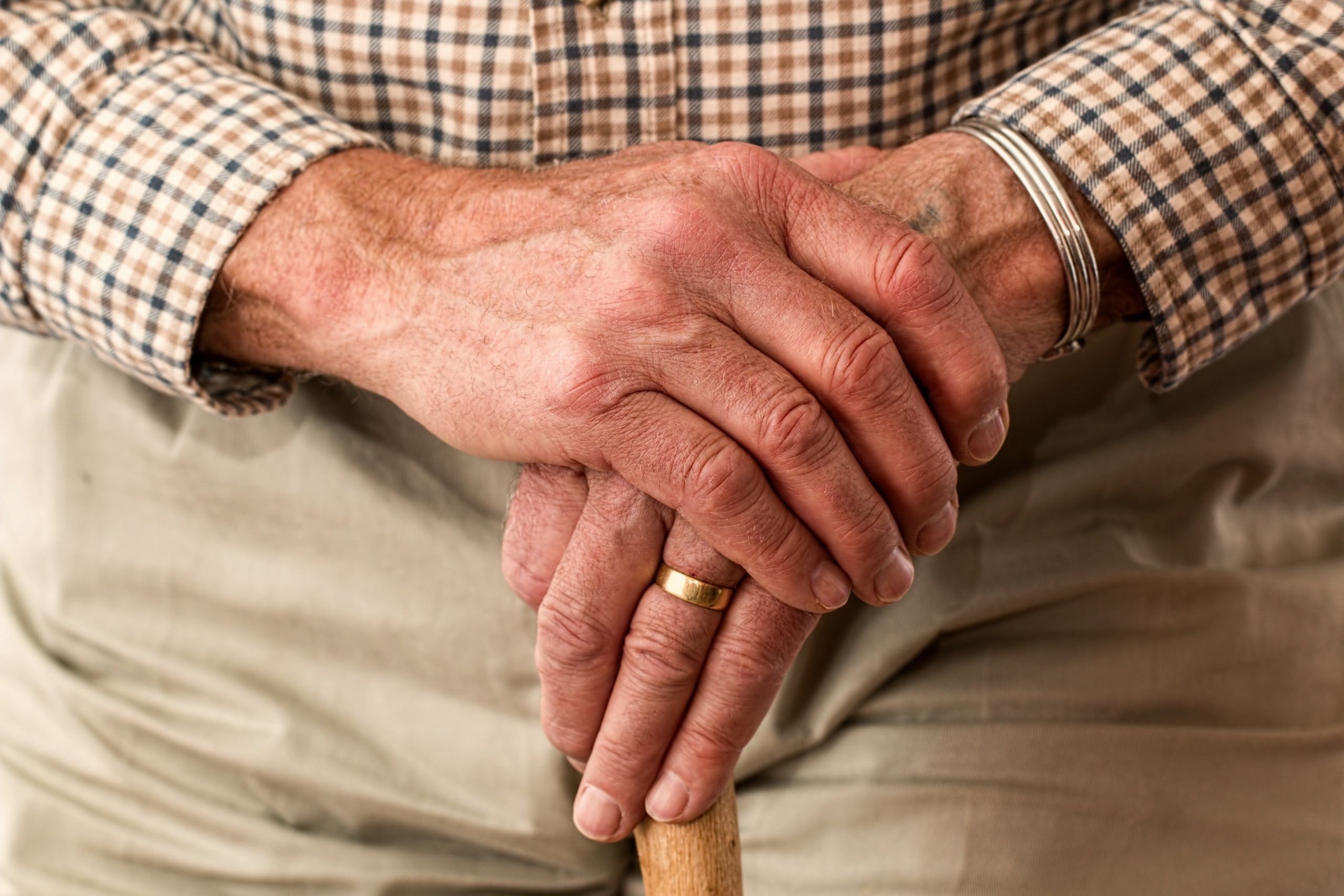 Older mans hands holding a cane