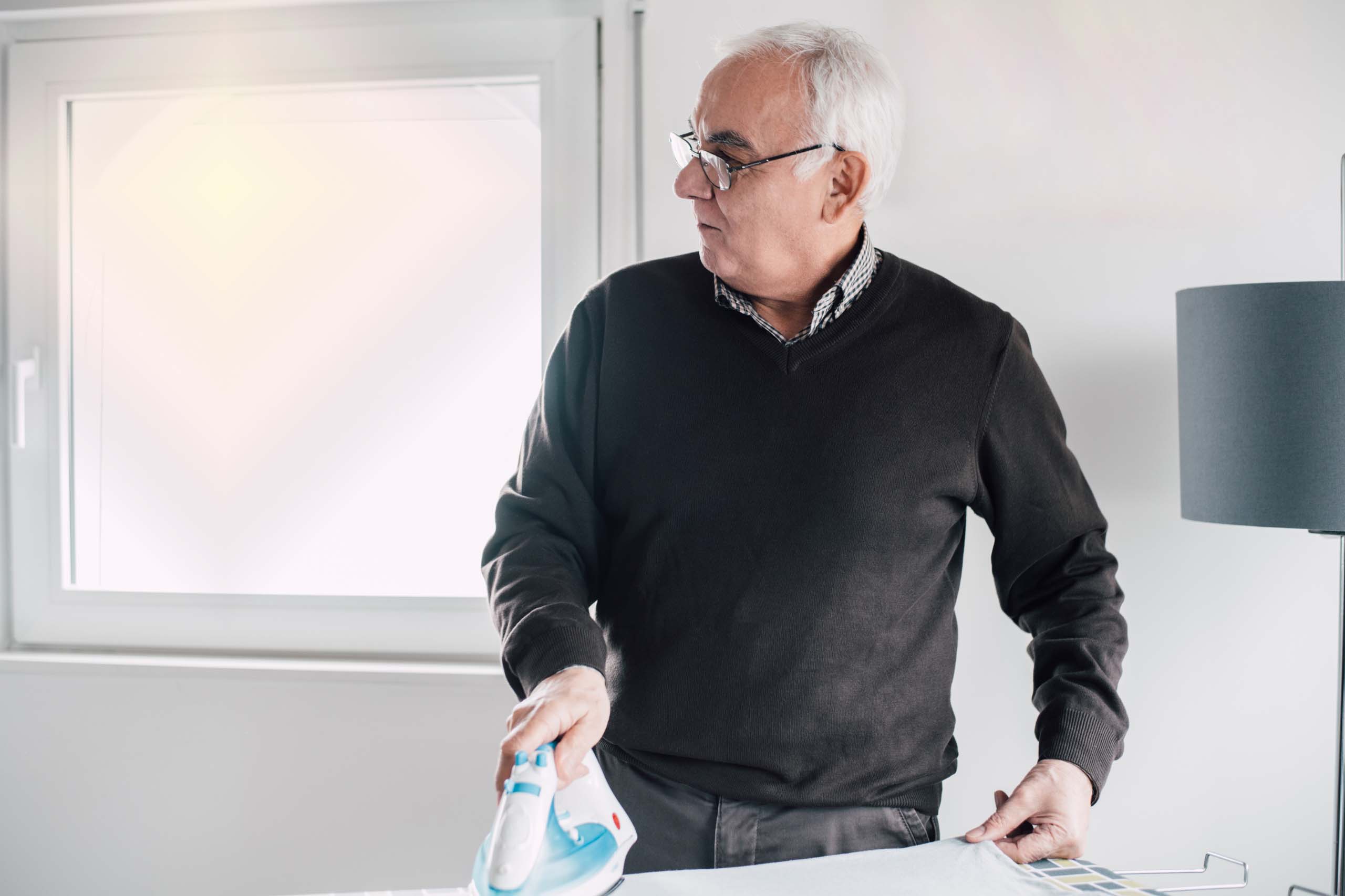 Older man ironing clothes