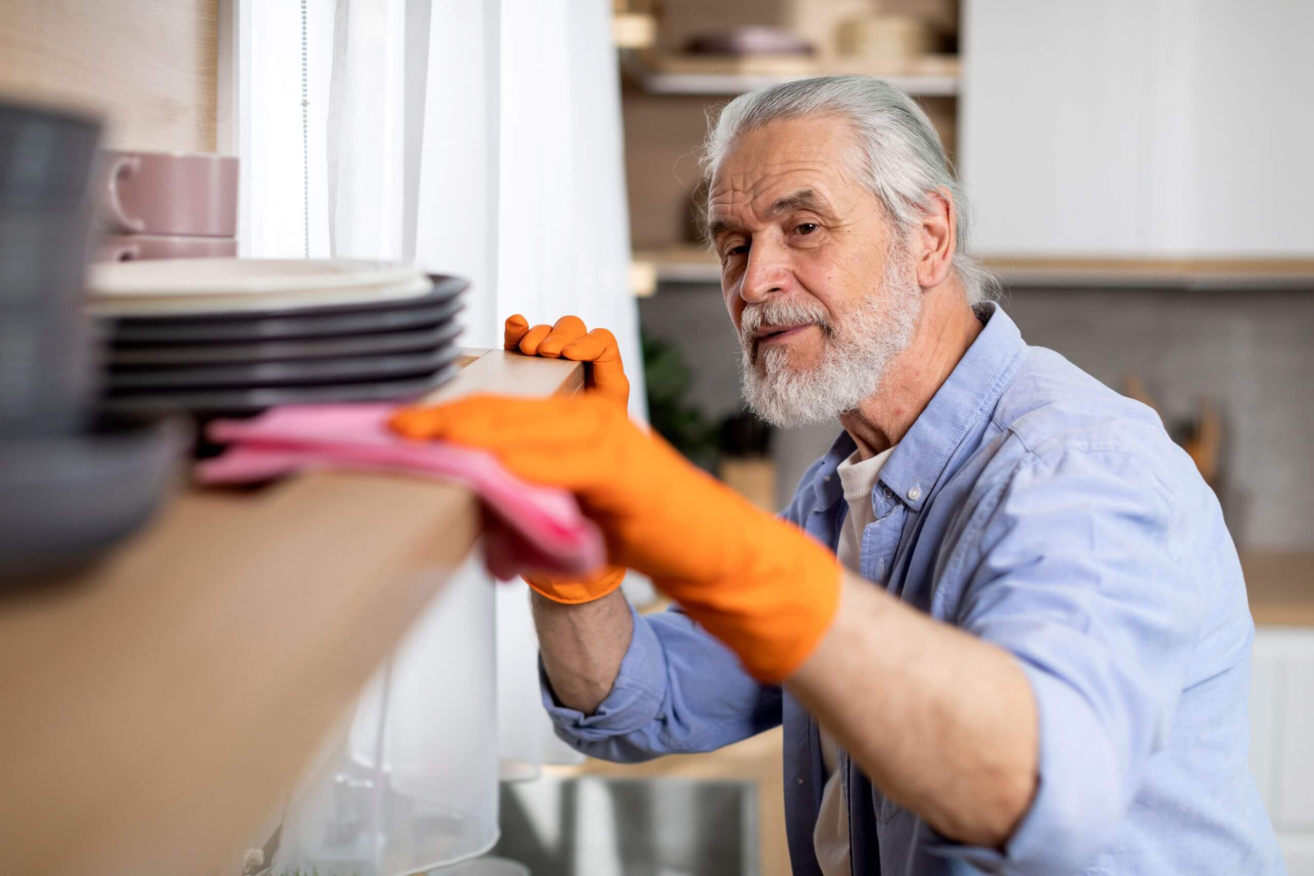 An older man wiping down a surface with a cleaning cloth